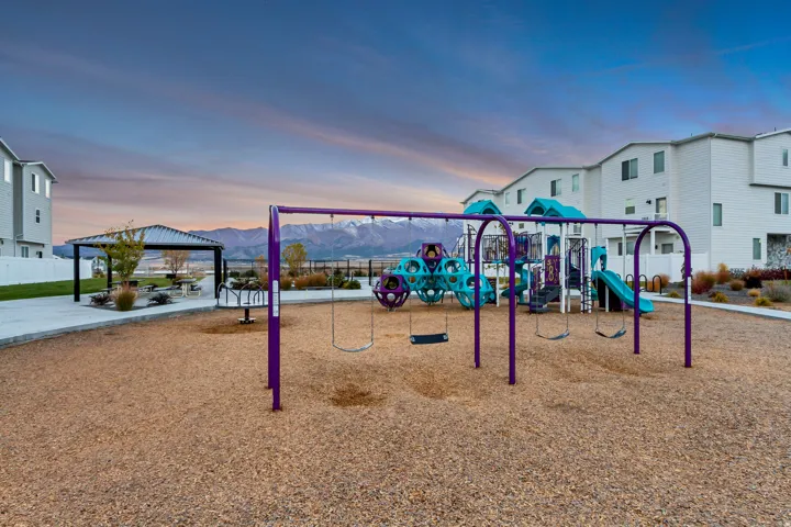Community playground featuring swings, multi-level play structures, and a dedicated picnic area with a covered gazebo