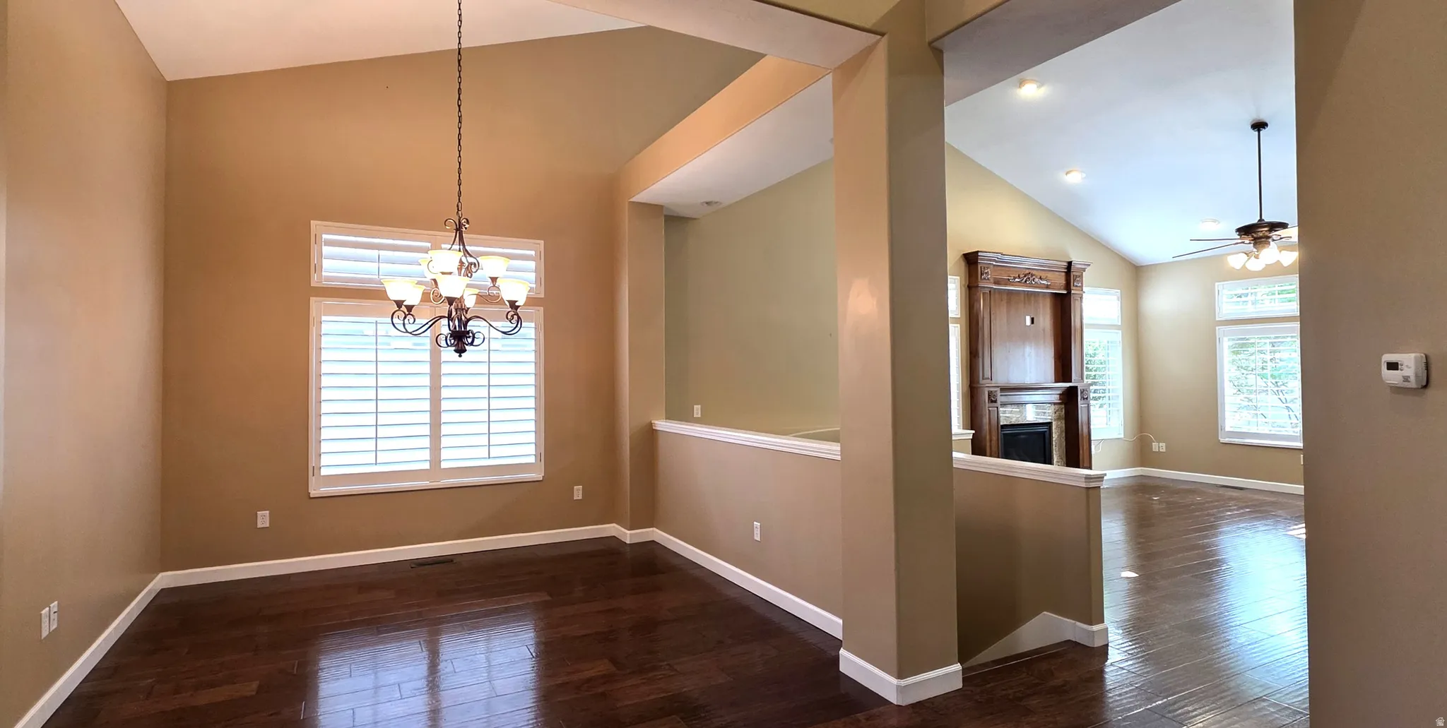 Vaulted ceilings, dark wood-finish flooring, plantation shutters, and an ornate chandelier