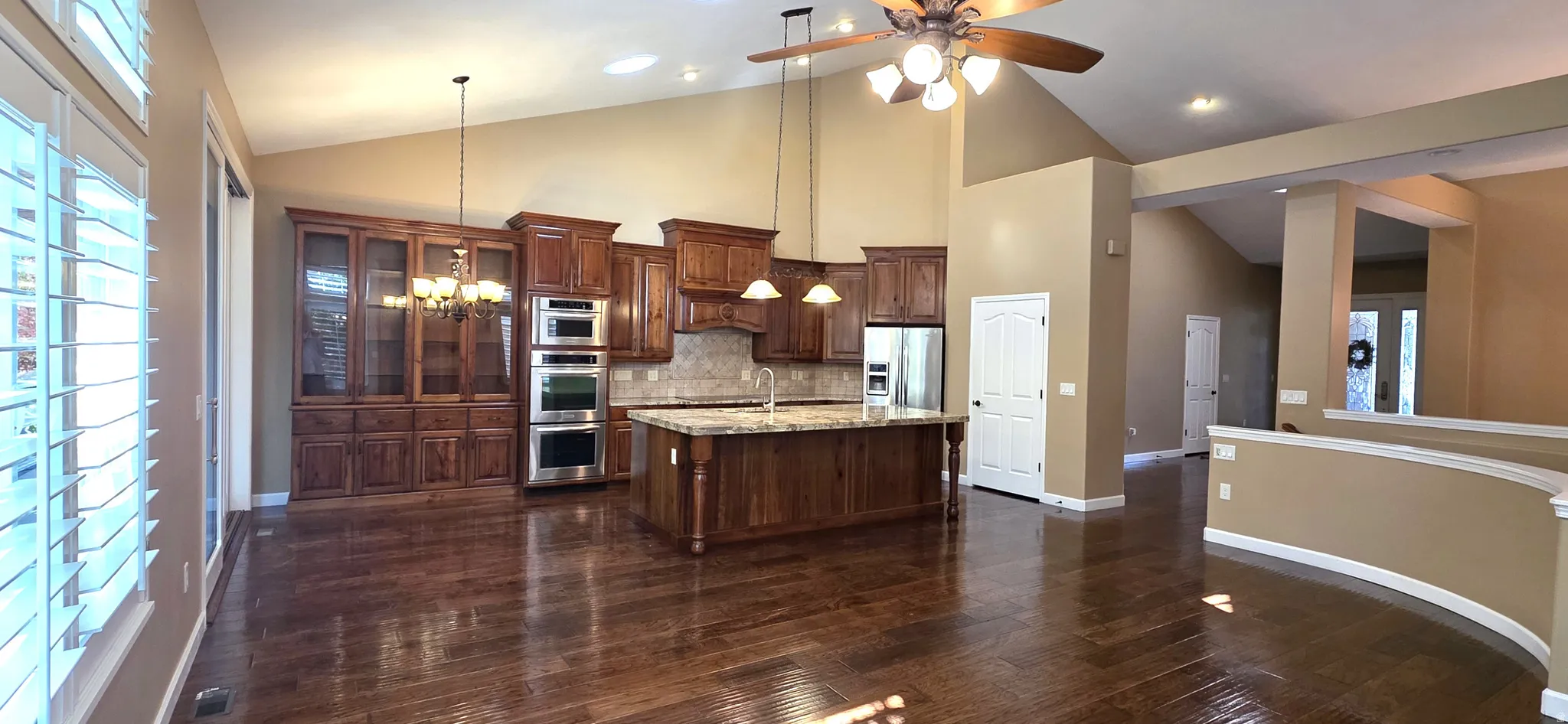 Vaulted ceilings, wood-finish flooring, custom cabinetry, kitchen island with built-in sink, and stainless steel appliances
