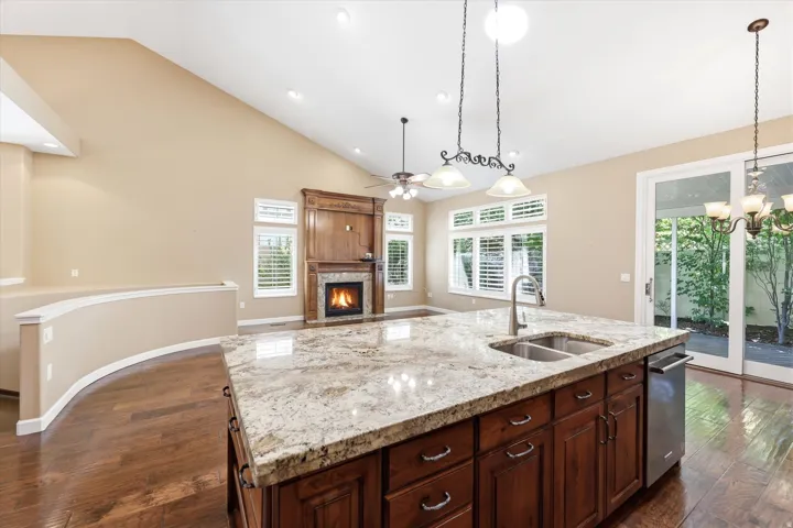 Kitchen island with stone-finish countertop, double basin sink, and stainless steel dishwasher