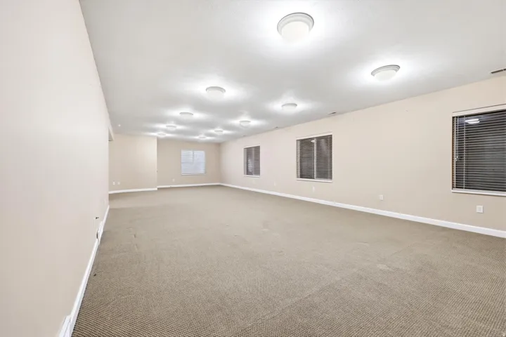 Expansive great room with neutral carpeting, light-toned walls, and multiple flush-mount ceiling lights