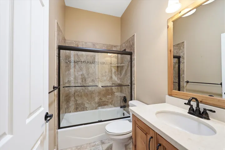 Bathroom featuring a wood-finish vanity with a light-toned countertop and an undermount sink