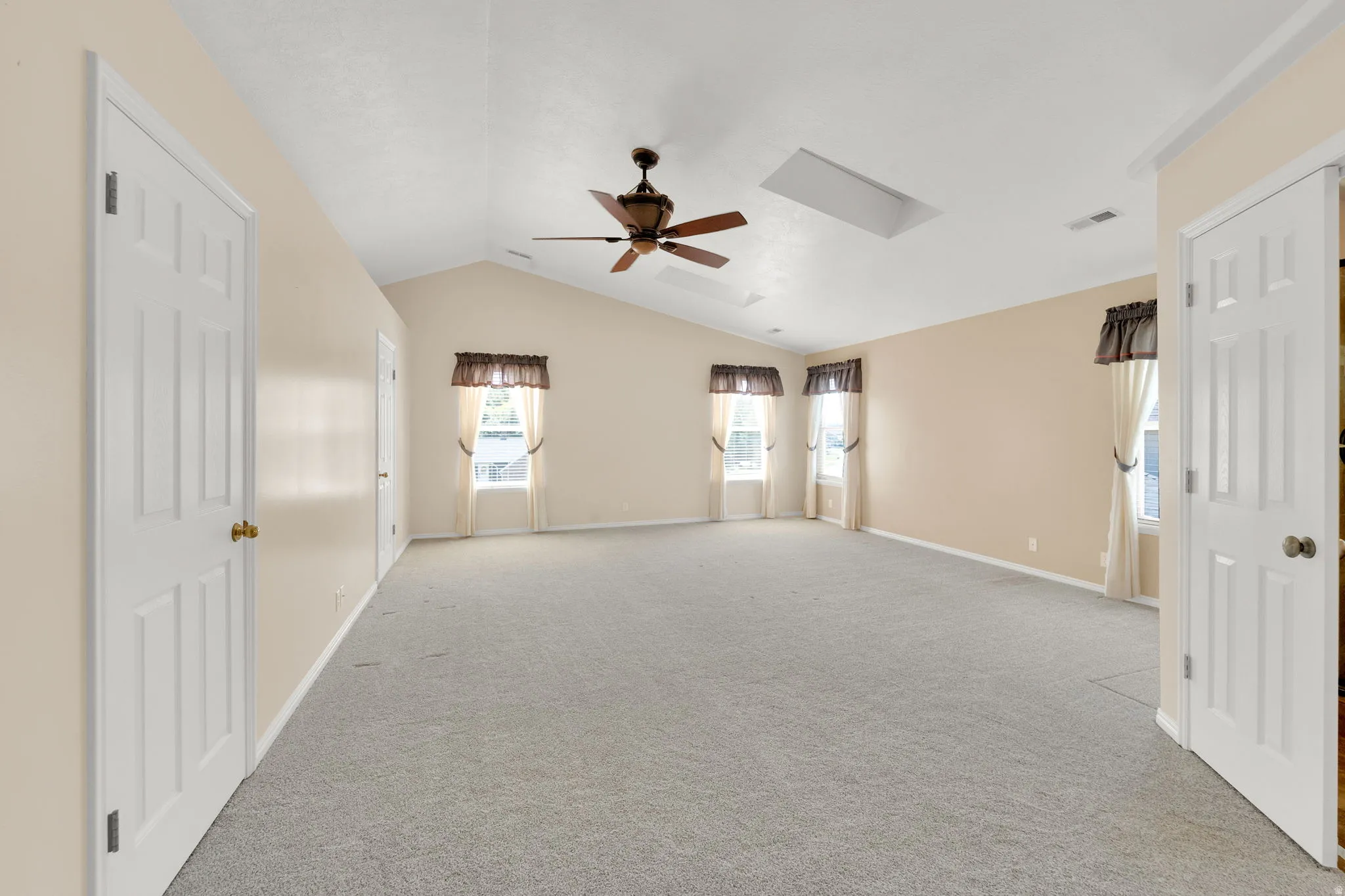 Owners Suite multiple windows, a ceiling fan, and a skylight