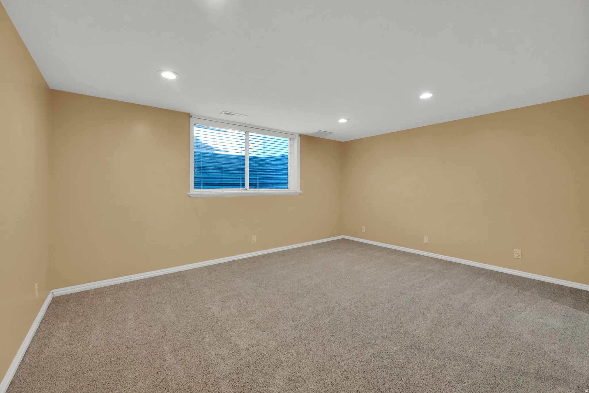 Spacious room featuring neutral-toned walls, recessed lighting, and plush carpeting