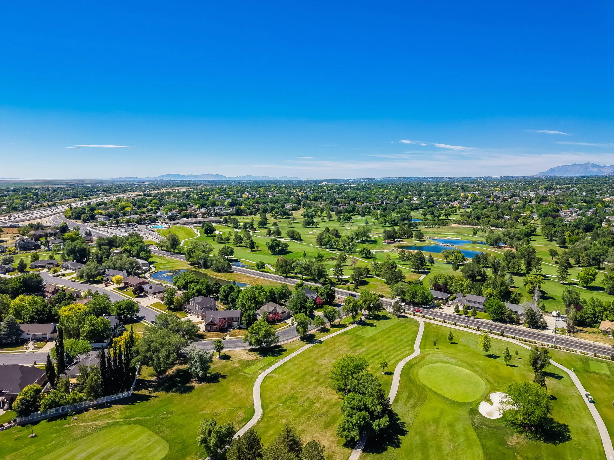 Expansive golf course setting featuring manicured greens, sand traps, and water features