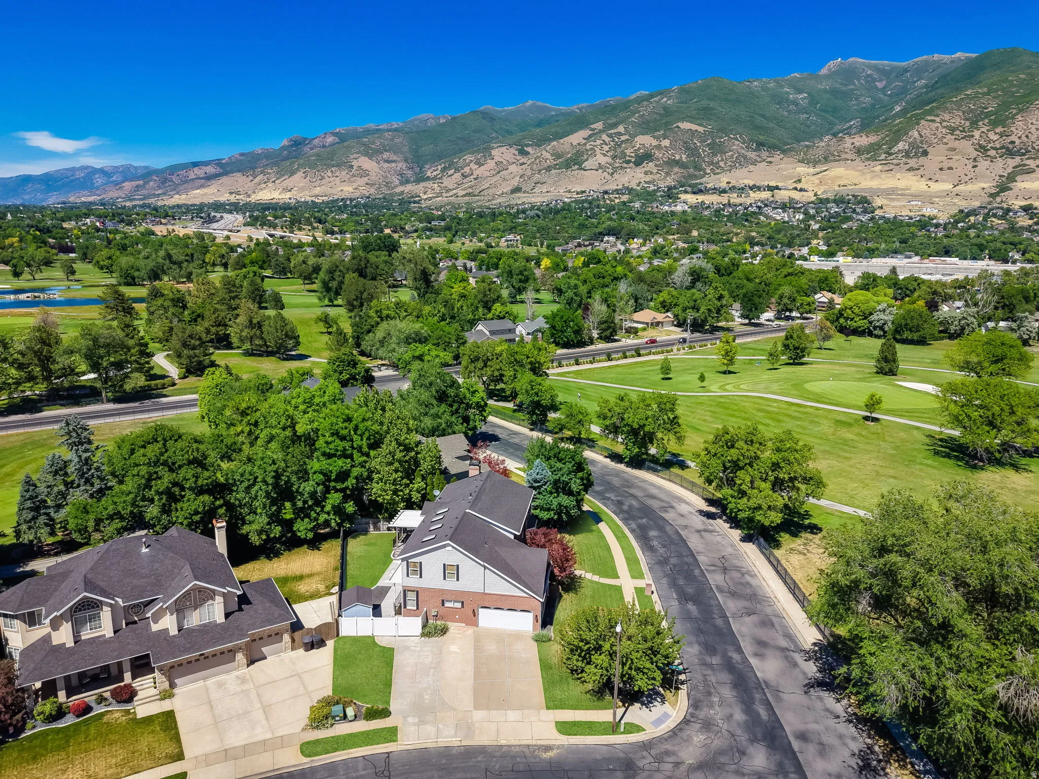 Aerial perspective showcasing the residential street with verdant trees and a distant golf course