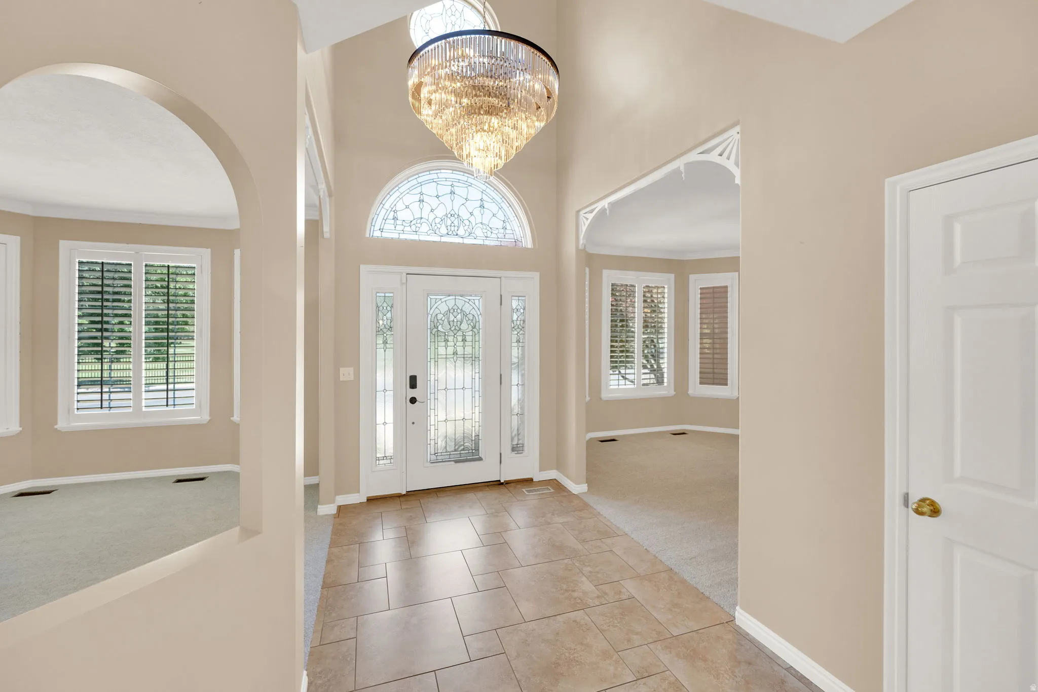 Two-story foyer featuring tile flooring, a decorative chandelier, and a transom window above the main entry