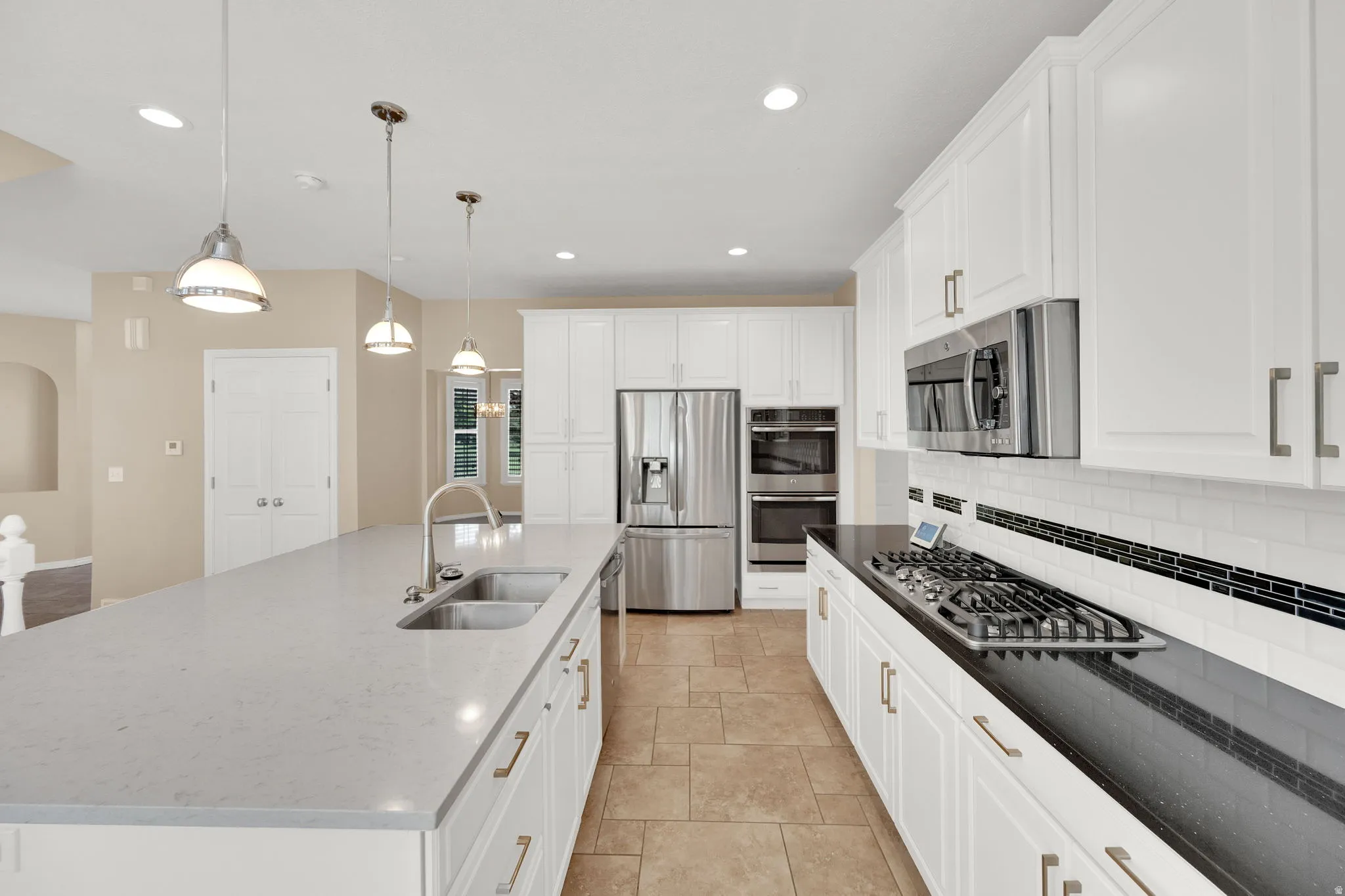 Gourmet kitchen featuring a spacious island with, stainless- steel appliances, white cabinetry, a gas cooktop, and tile flooring