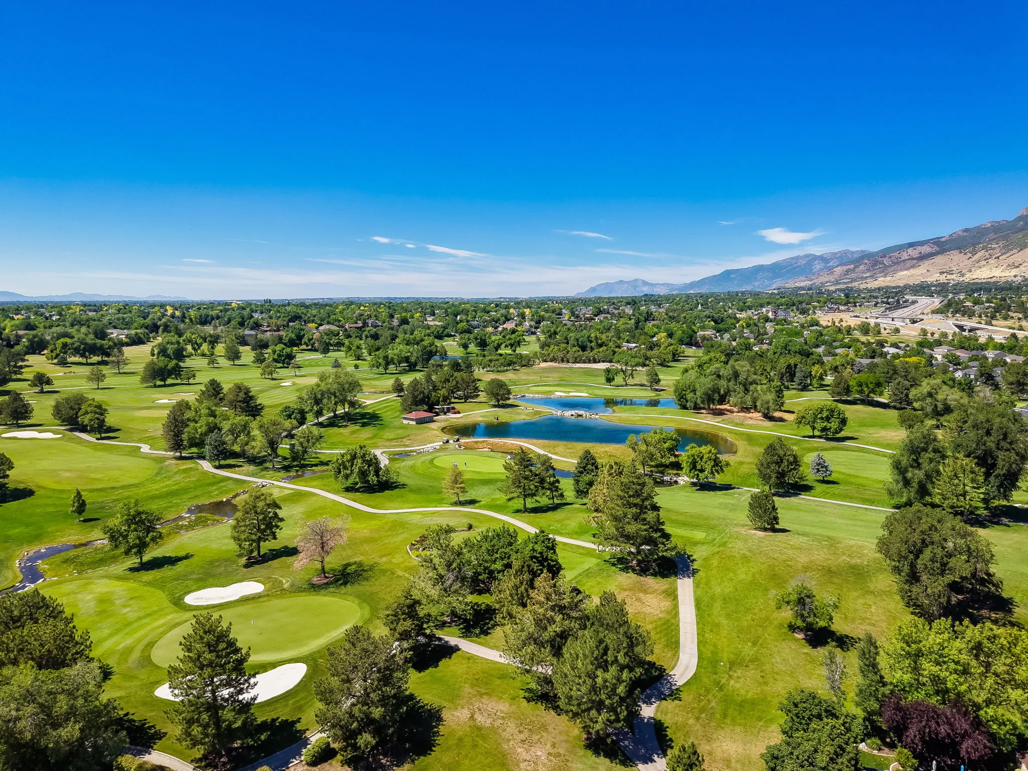 Expansive golf course landscape featuring multiple greens, sand traps, and water features