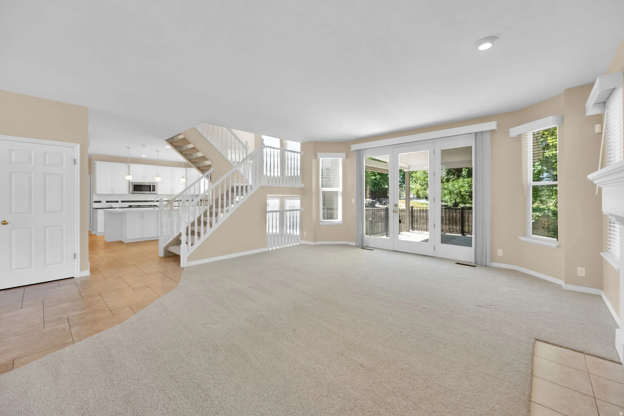 Spacious carpeted living area with abundant natural light from multiple windows and glass patio doors