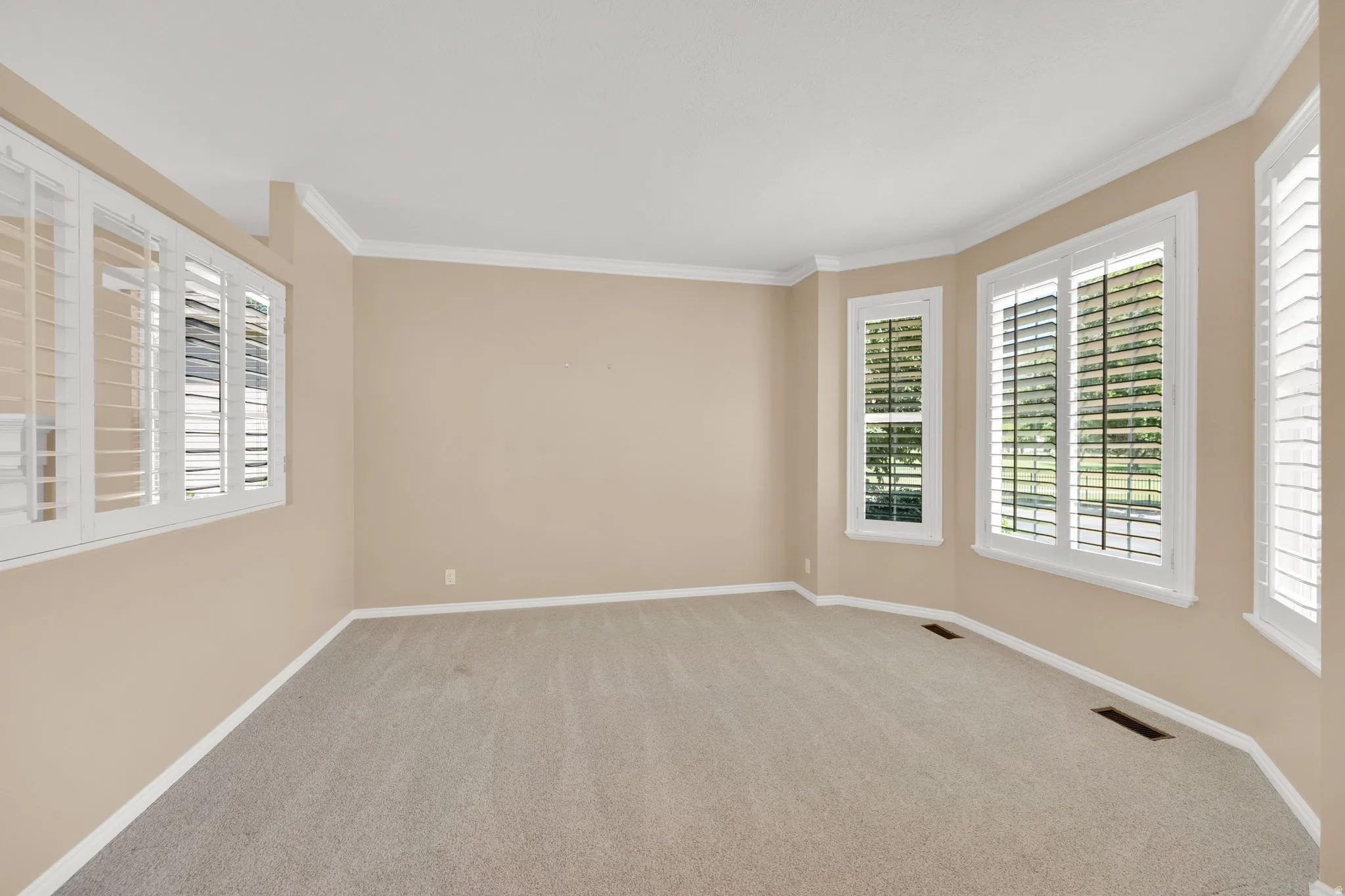 Spacious room featuring a bay window with plantation shutters.