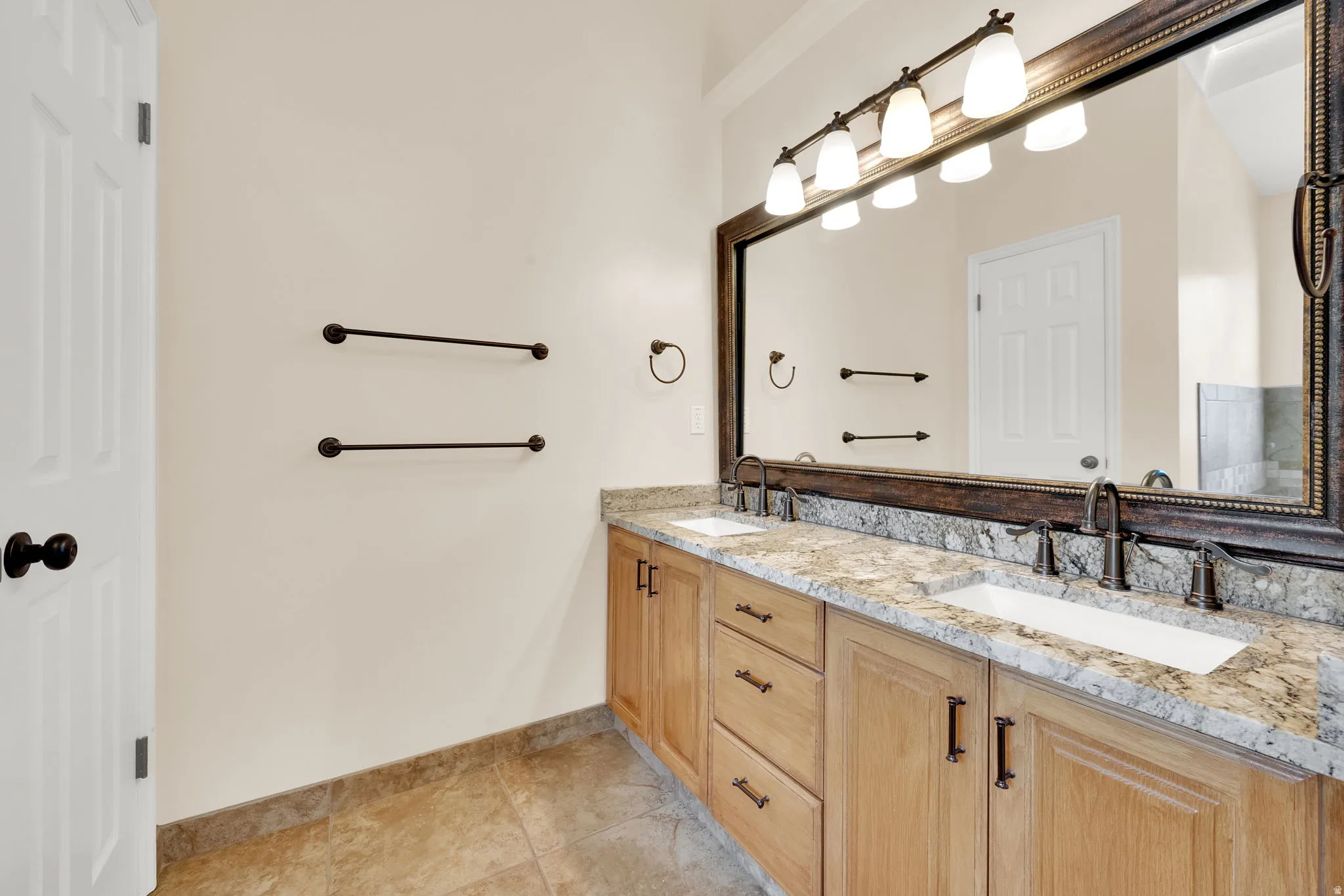 Double vanity featuring granite countertops, undermount sinks, and bronze-finish hardware