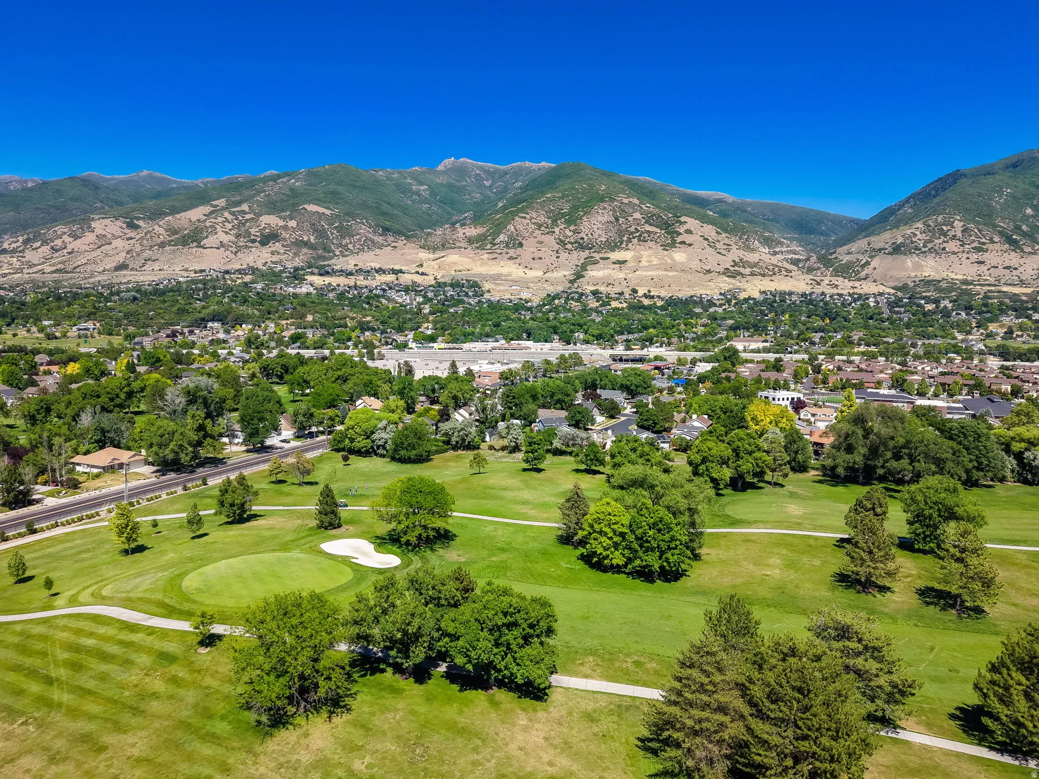 Expansive golf course setting featuring green fairways, sand traps, and mature trees