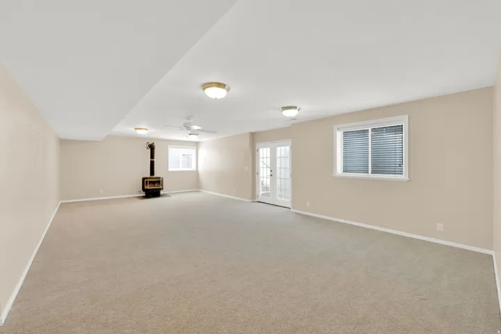 Spacious Great room featuring neutral carpeting, light beige walls, a gas stove, white trim, and a ceiling fan