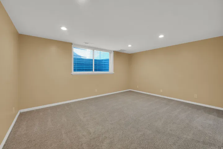 Spacious room featuring neutral-toned walls, recessed lighting, and plush carpeting