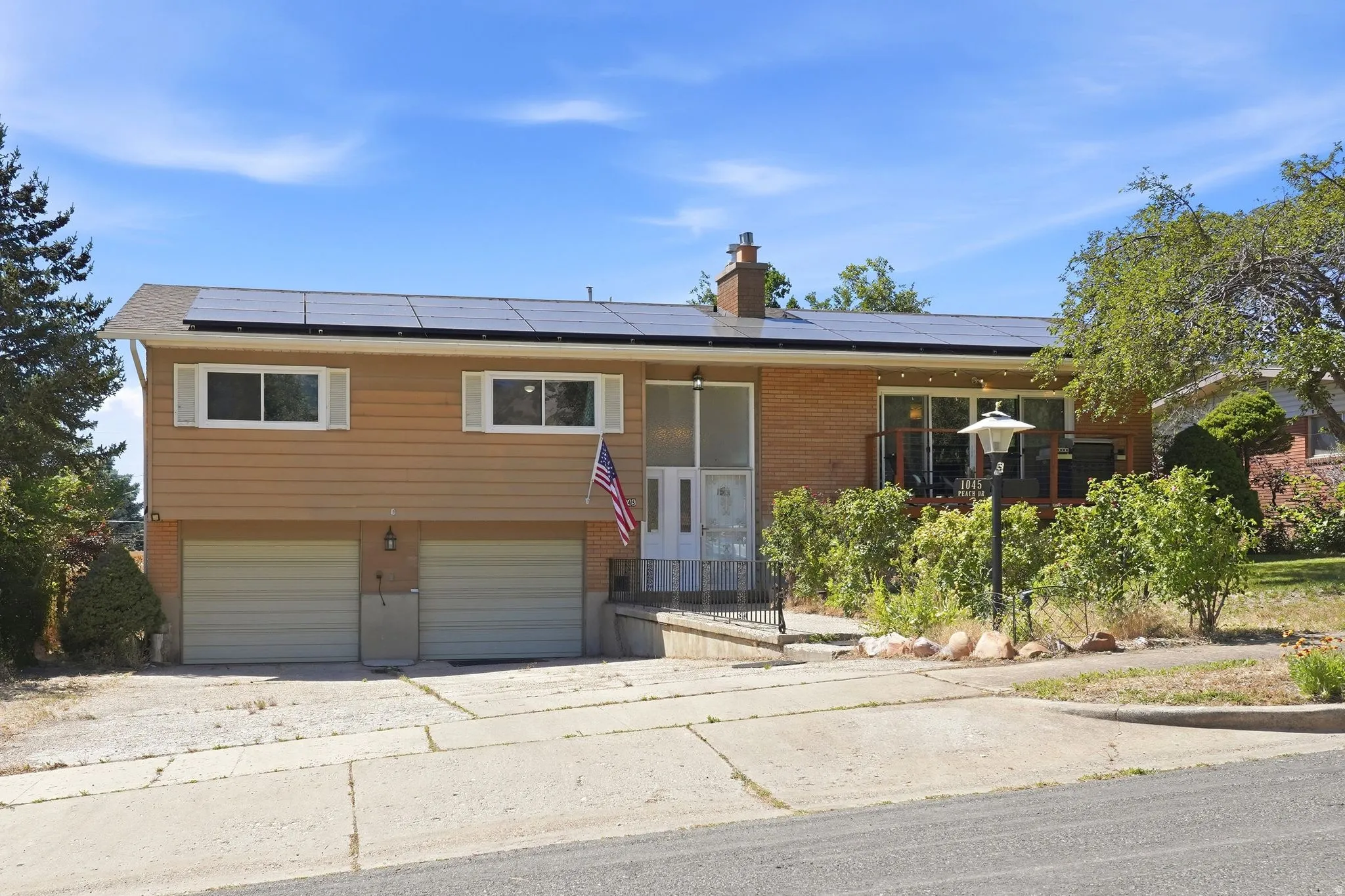 Split-level residence featuring a brick and siding exterior, integrated solar panels, and a two-car garage