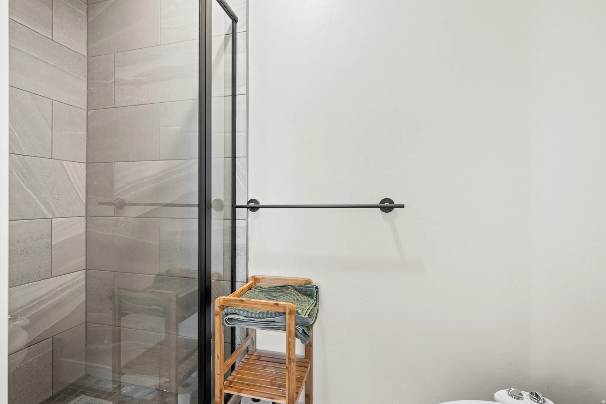 Shower enclosure featuring black-framed clear glass and a light-toned tiled interior