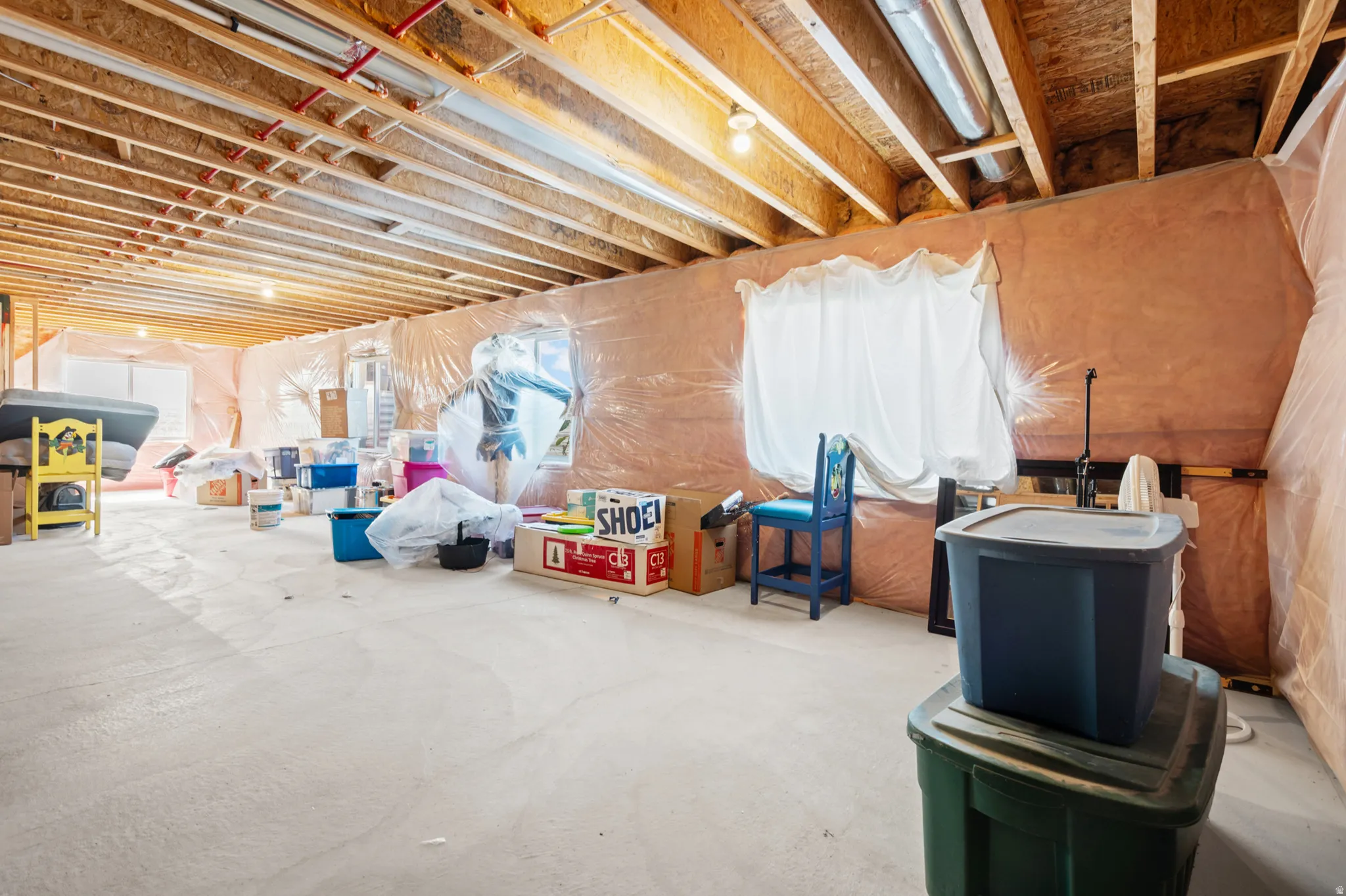 Unfinished basement with exposed wood joists and insulation-wrapped walls
