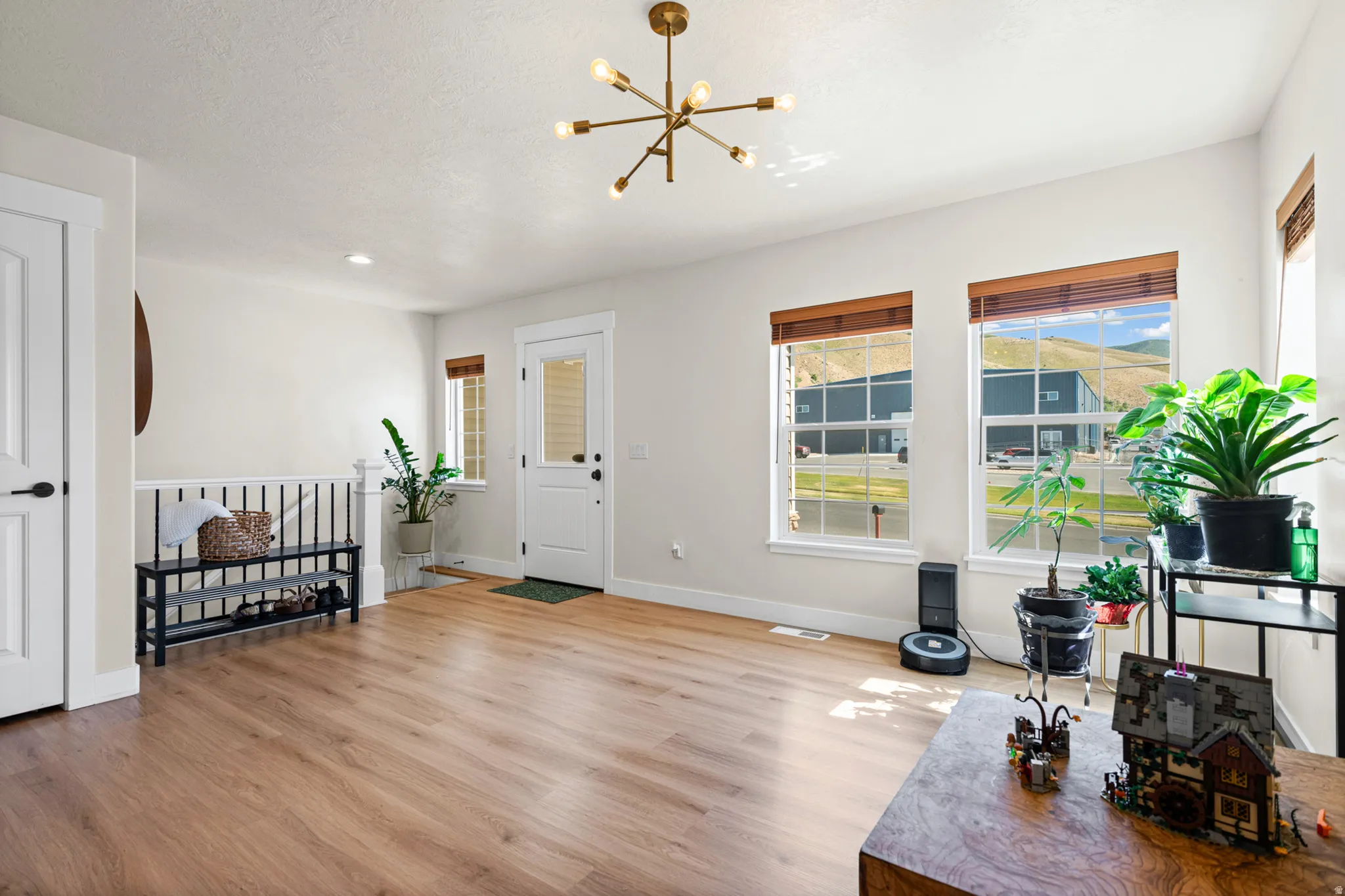 Spacious entry with wood-finish flooring, white trim, and a contemporary brass chandelier