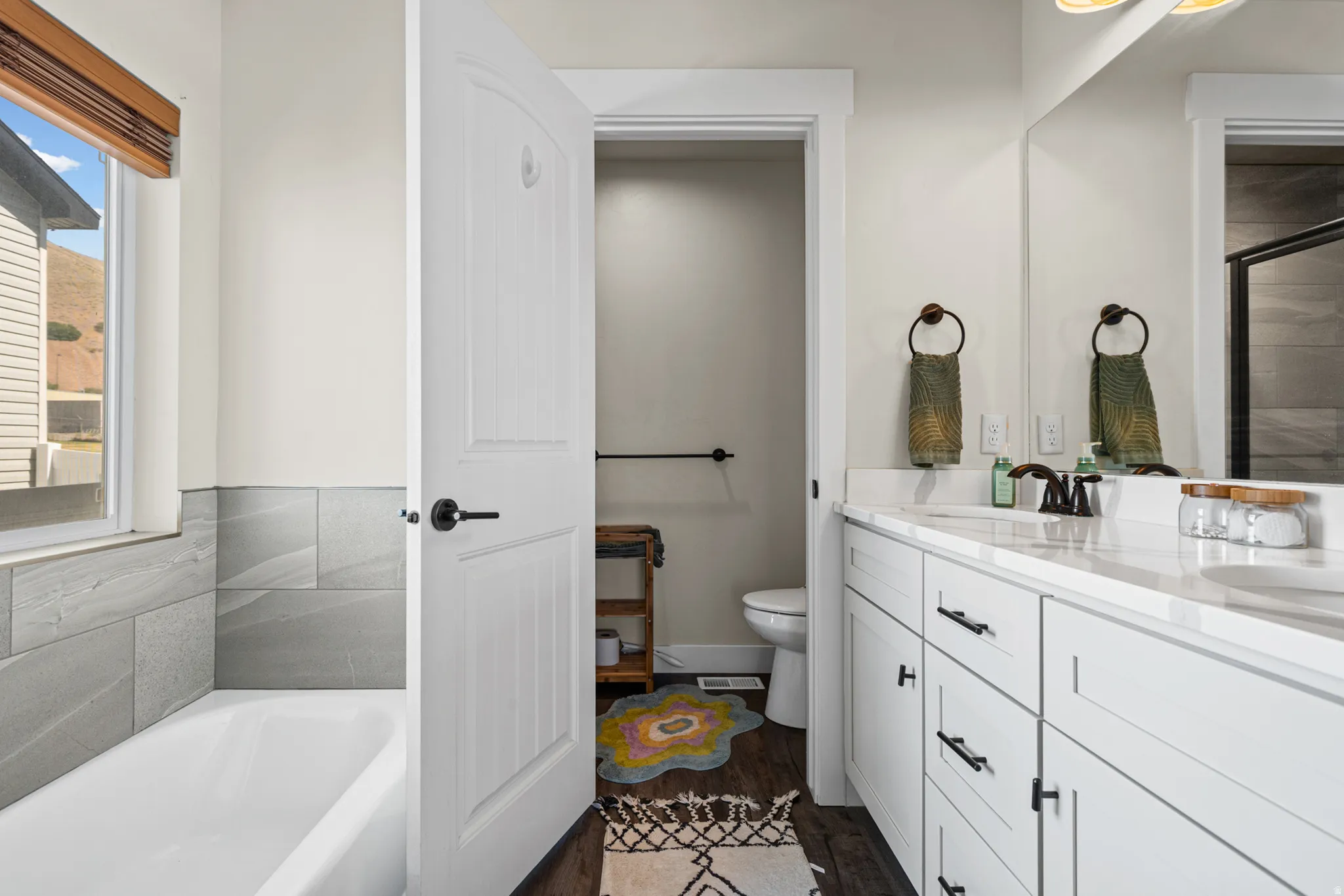 Contemporary bathroom featuring a double vanity with white cabinetry and dark hardware, set under a large mirror