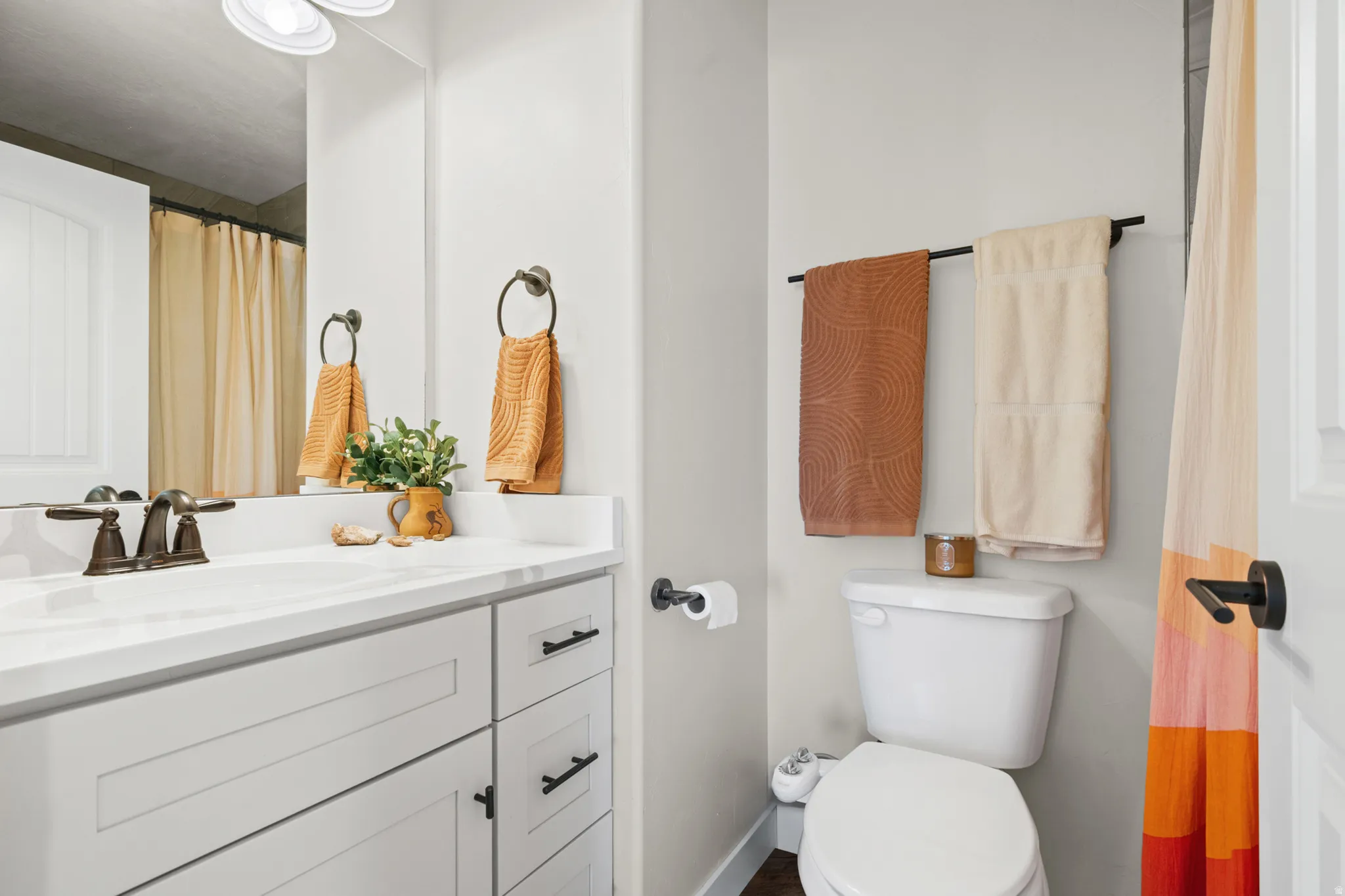 Bathroom featuring a white vanity with integrated sink, bronze-finish faucet, and a large wall-mounted mirror