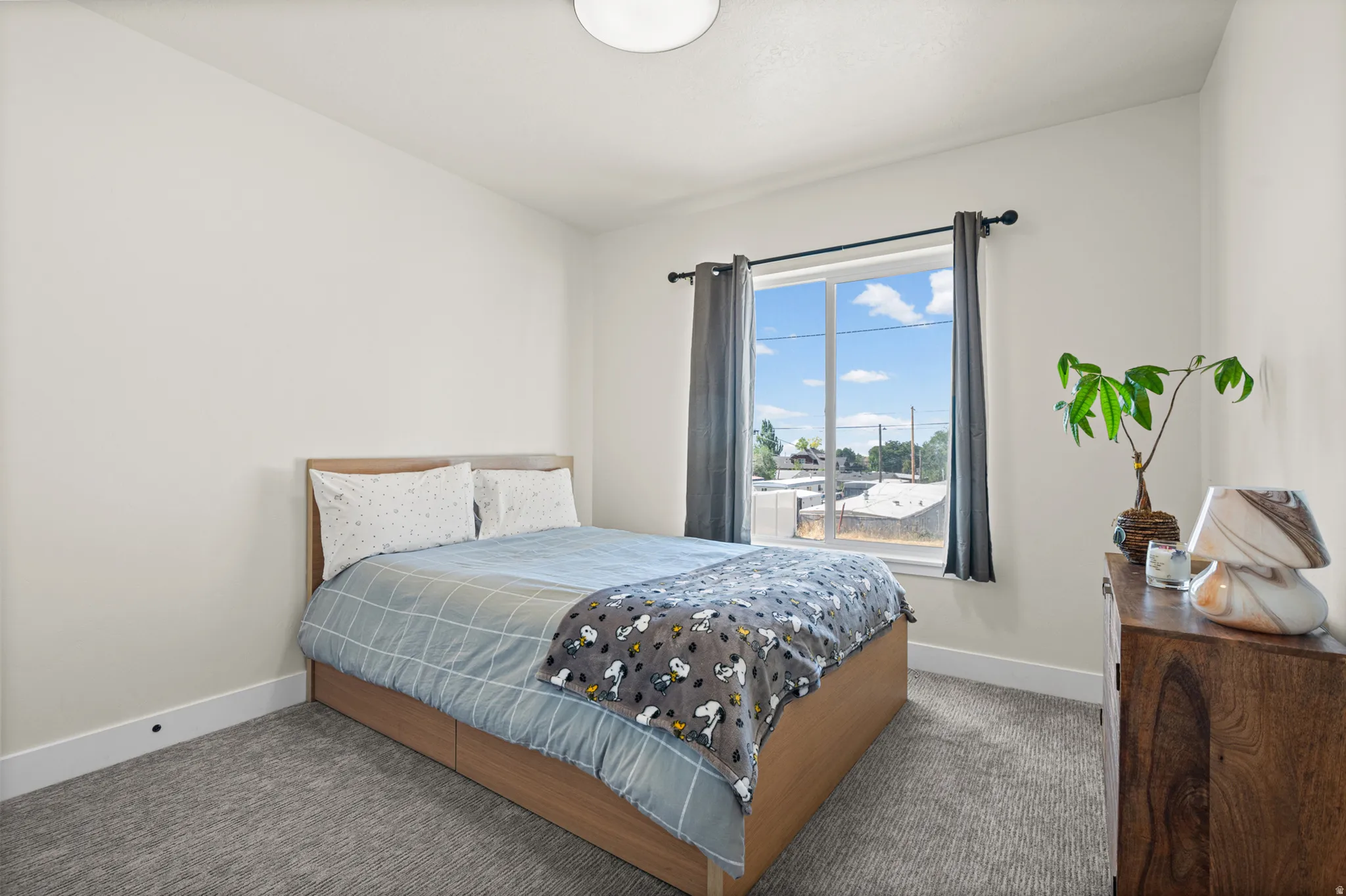 Bedroom featuring carpet flooring, a large window with white trim, and a flush-mount ceiling light
