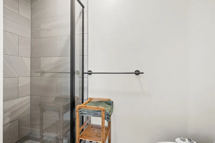 Shower enclosure featuring black-framed clear glass and a light-toned tiled interior
