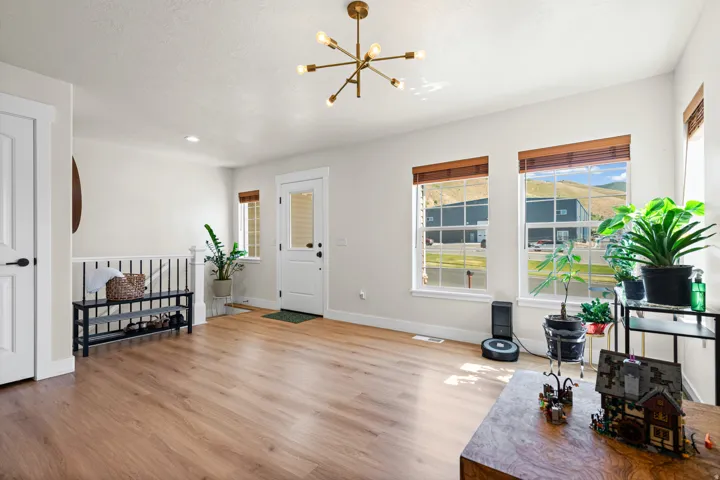 Spacious entry with wood-finish flooring, white trim, and a contemporary brass chandelier