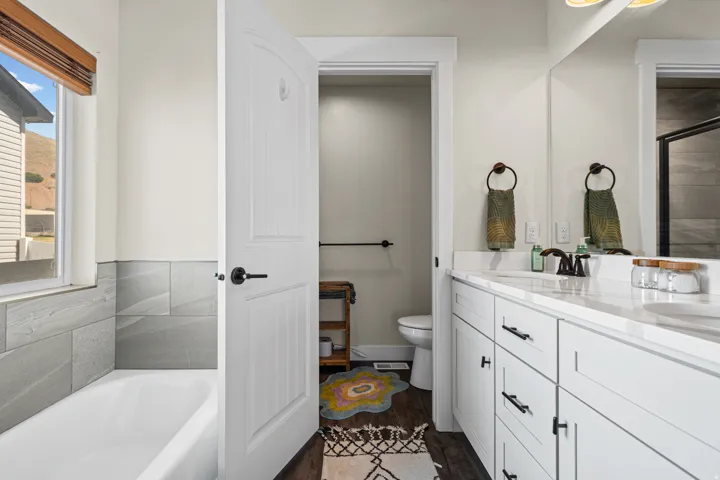 Contemporary bathroom featuring a double vanity with white cabinetry and dark hardware, set under a large mirror