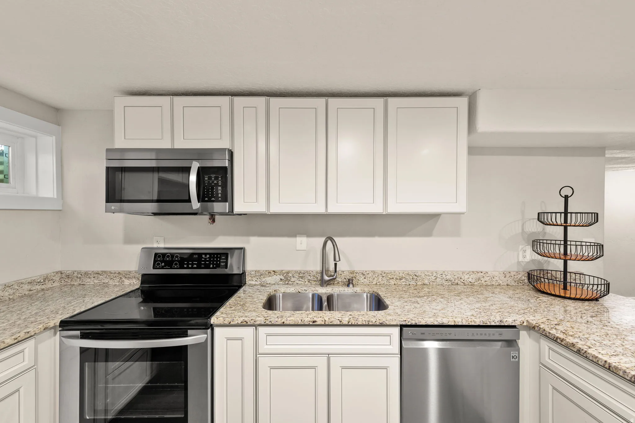 Modern kitchen featuring white shaker cabinetry, stainless steel appliances, speckled stone countertops, and a double basin sink with a gooseneck faucet!  Lots of Counter Space!
