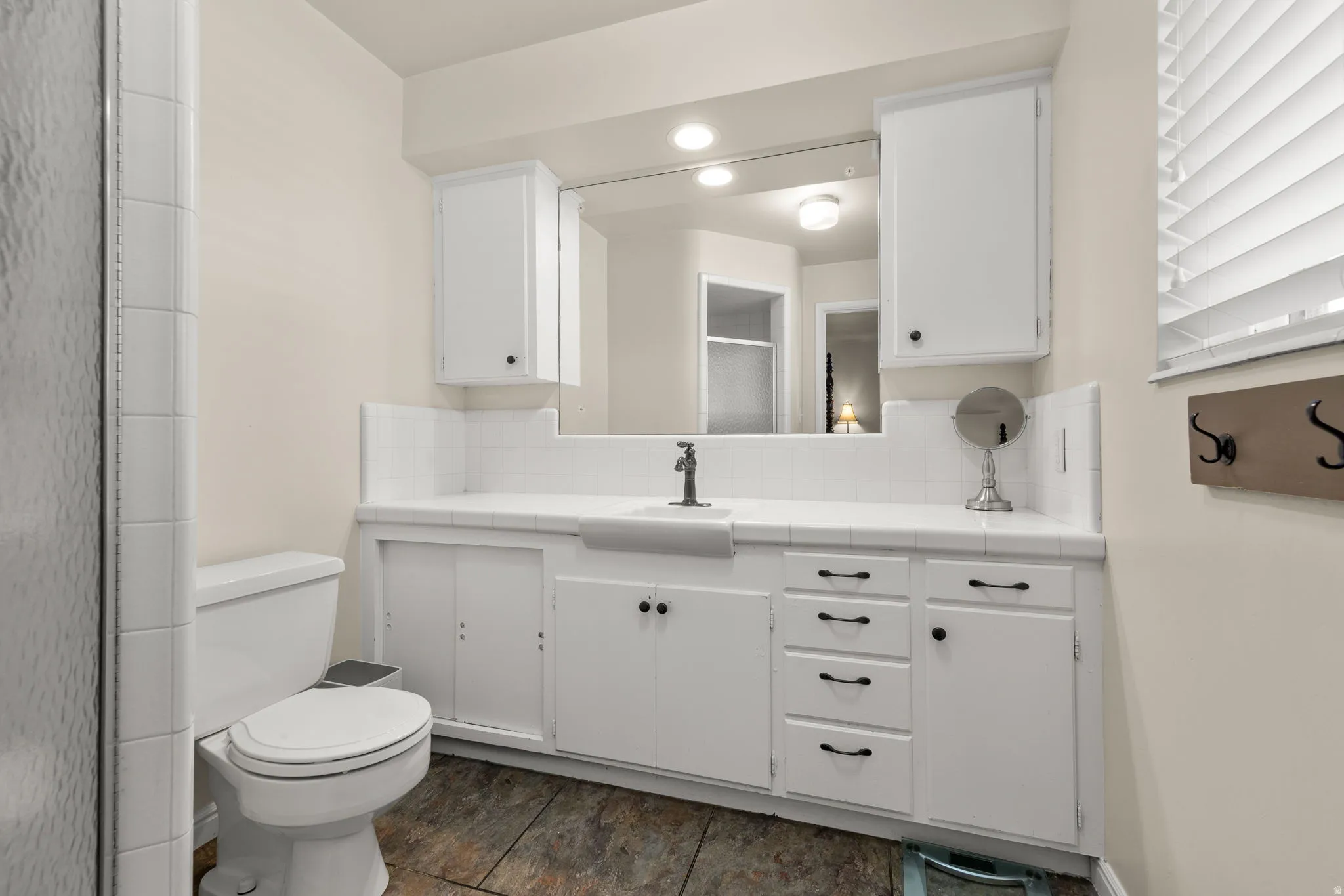 Adjoining Primary Private Bathroom with Toilet Sink & Shower and Easy Access Cabinets and Drawers.  Natural light from large Window.
