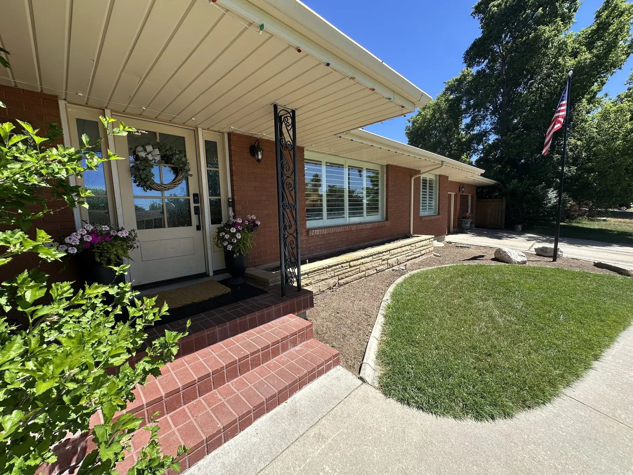 Brick exterior with a covered entryway, decorative wrought iron support column, brick steps, and a manicured lawn!