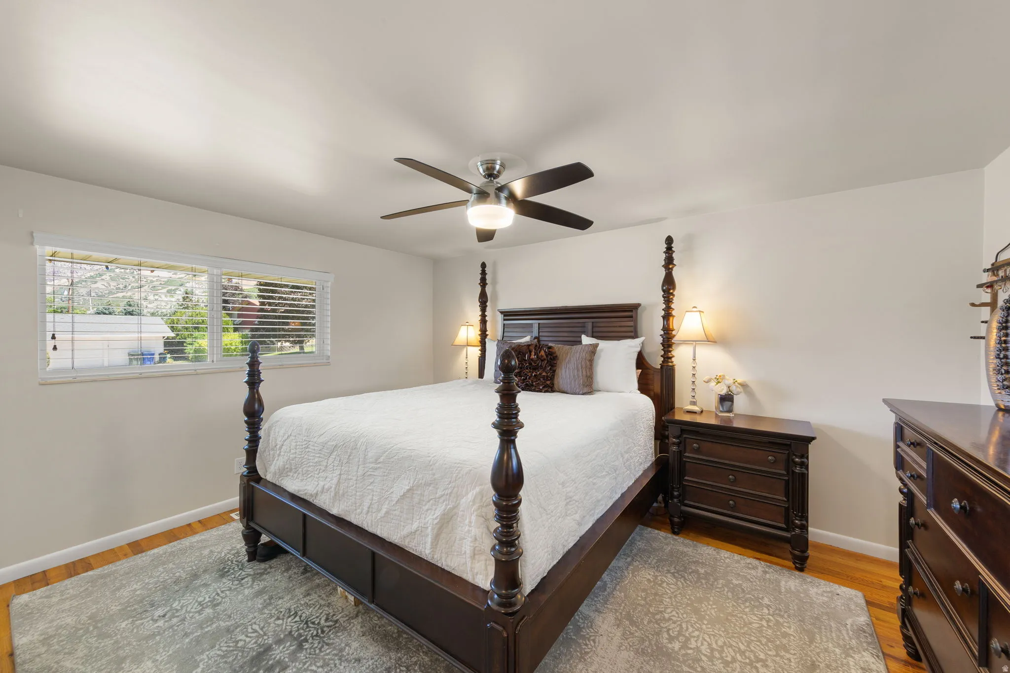 Primary bedroom instantly puts you at ease with ceiling fan and large windows on each side of California King Poster Bed.  Beautiful Natural Solid Wood Floors.