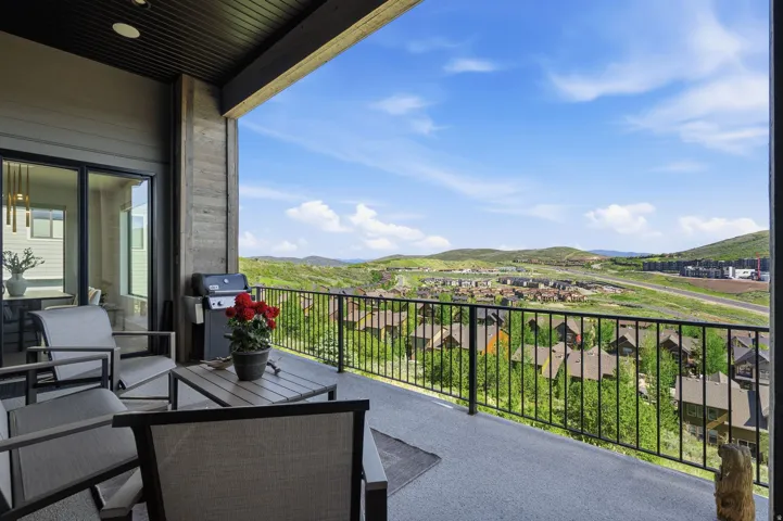 Expansive outdoor balcony featuring a concrete surface, black metal railing, and wood-finish ceiling
