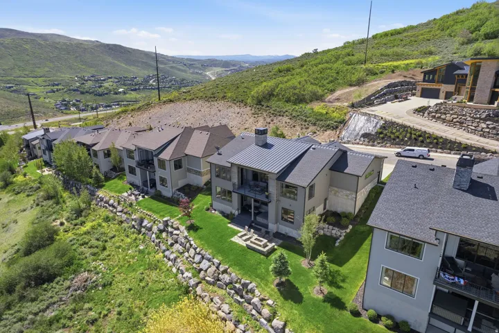 Modern exterior featuring a dark metal roof, stone chimney, and multiple balconies