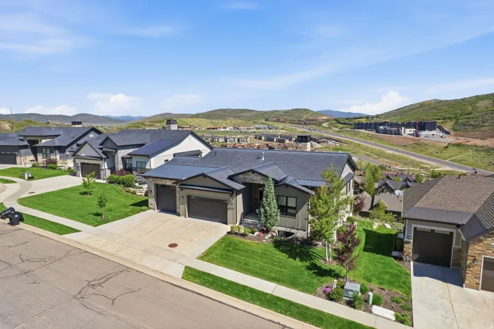 Contemporary-style residence with a dark gray exterior, stone accents, and a multi-car garage