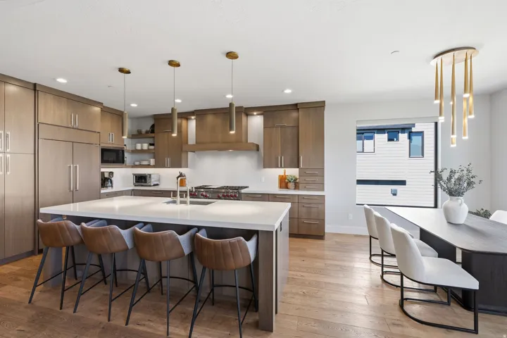 Gourmet kitchen featuring a large island with seating, stainless steel appliances, wood-finish cabinetry, and light wood-finish flooring