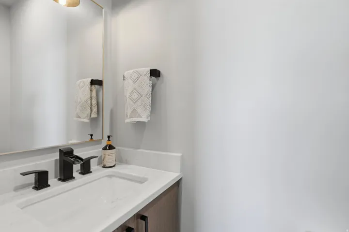 Modern vanity featuring an integrated rectangular sink, light-colored countertop, and dark-finish fixtures