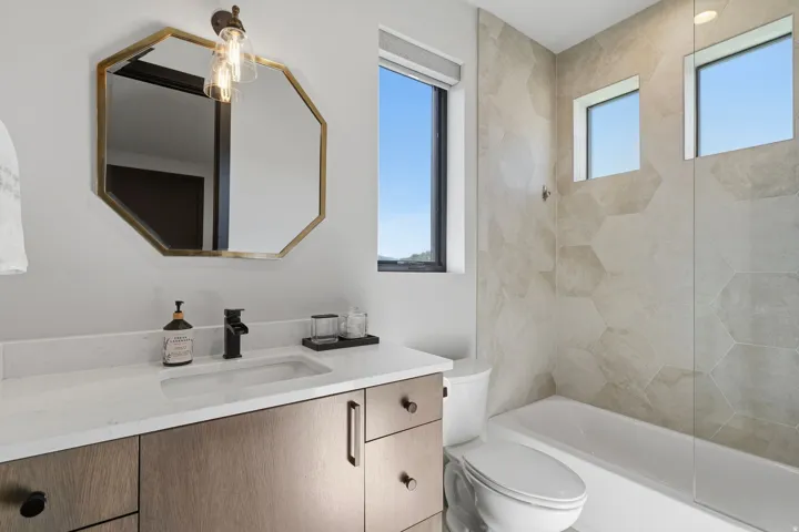 Bathroom vanity featuring a rectangular undermount sink, a white stone countertop, and wood-finish cabinetry with dark hardware