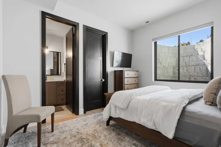 Bedroom featuring a large window, dark trim, and an en-suite bathroom with a vanity and mirror