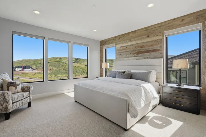 Spacious room featuring floor-to-ceiling windows, a textured wood accent wall, recessed lighting, and light-toned carpeting