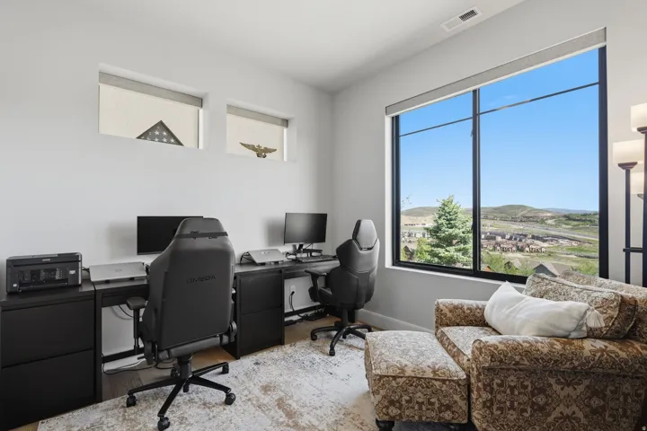 Spacious room featuring a large picture window, a desk area with built-in cabinetry, two horizontal accent windows, and light-toned walls