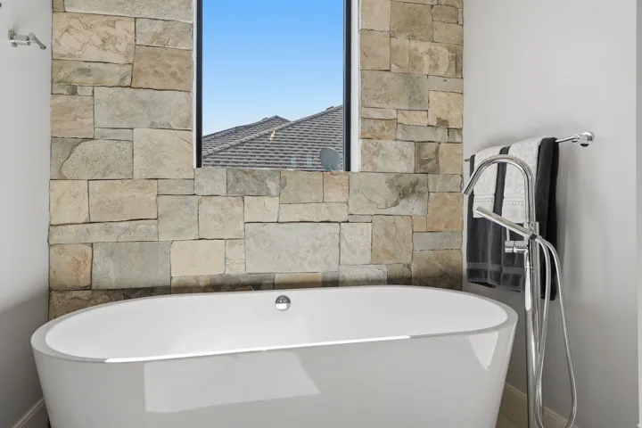 Freestanding soaking tub with a floor-mounted polished chrome faucet and hand shower