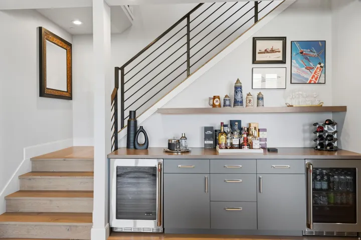 Built-in wet bar featuring gray cabinetry, stainless steel beverage refrigerators, and wood-finish countertops