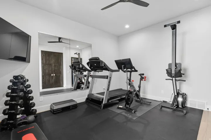 Dedicated fitness room featuring wall-mounted mirror, ceiling fan, recessed lighting, and rubber flooring