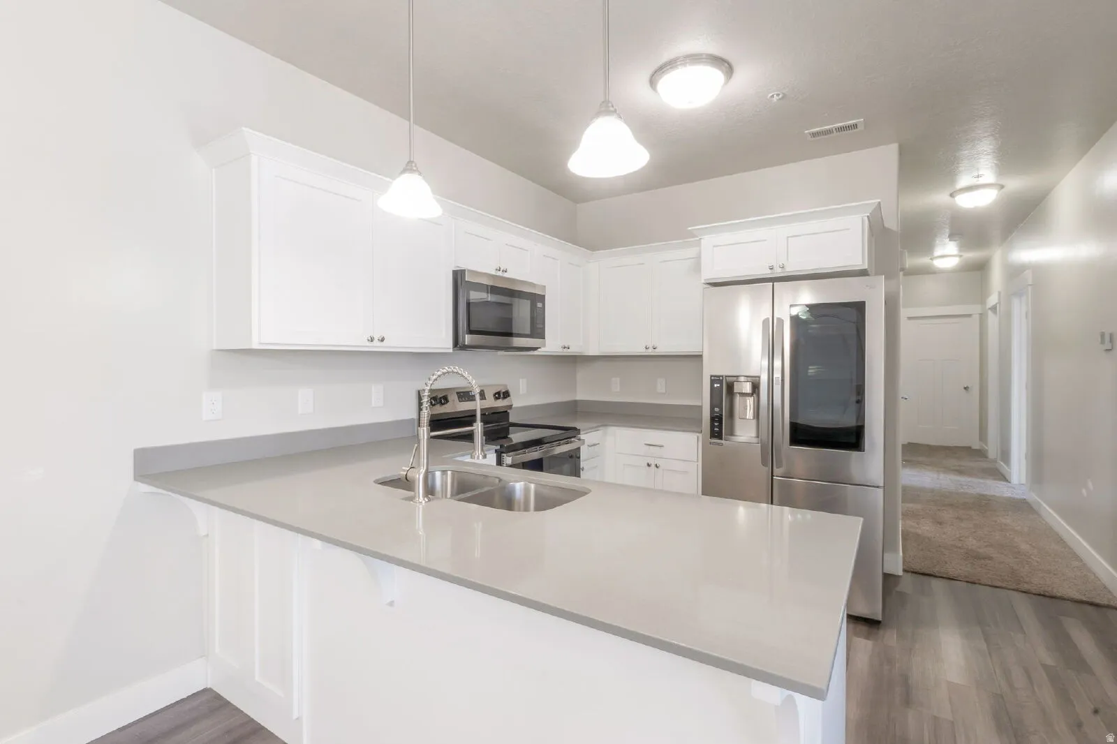 Kitchen featuring white cabinetry, light gray countertops, stainless steel appliances