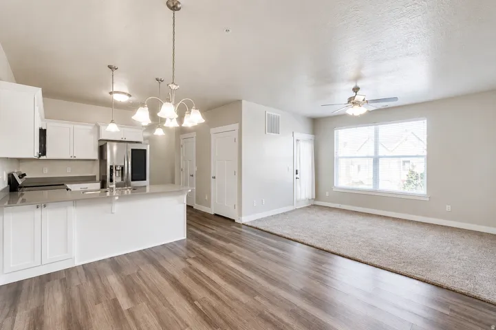 Open-concept living space featuring a modern kitchen with white cabinetry, stainless steel appliances, and a central island