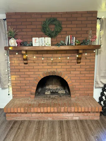 Brick fireplace with an arched firebox, a substantial wooden mantel, and a raised brick hearth