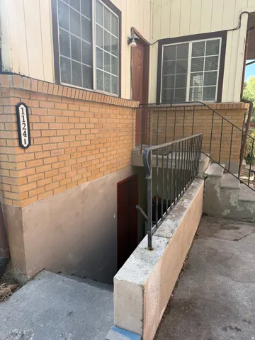 Terraced entry with a concrete walkway, brick facade, and decorative address plaque