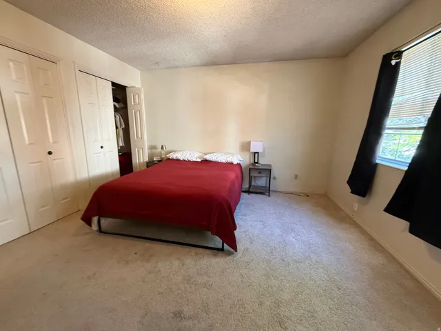 Carpeted room featuring a window with horizontal blinds, providing natural light